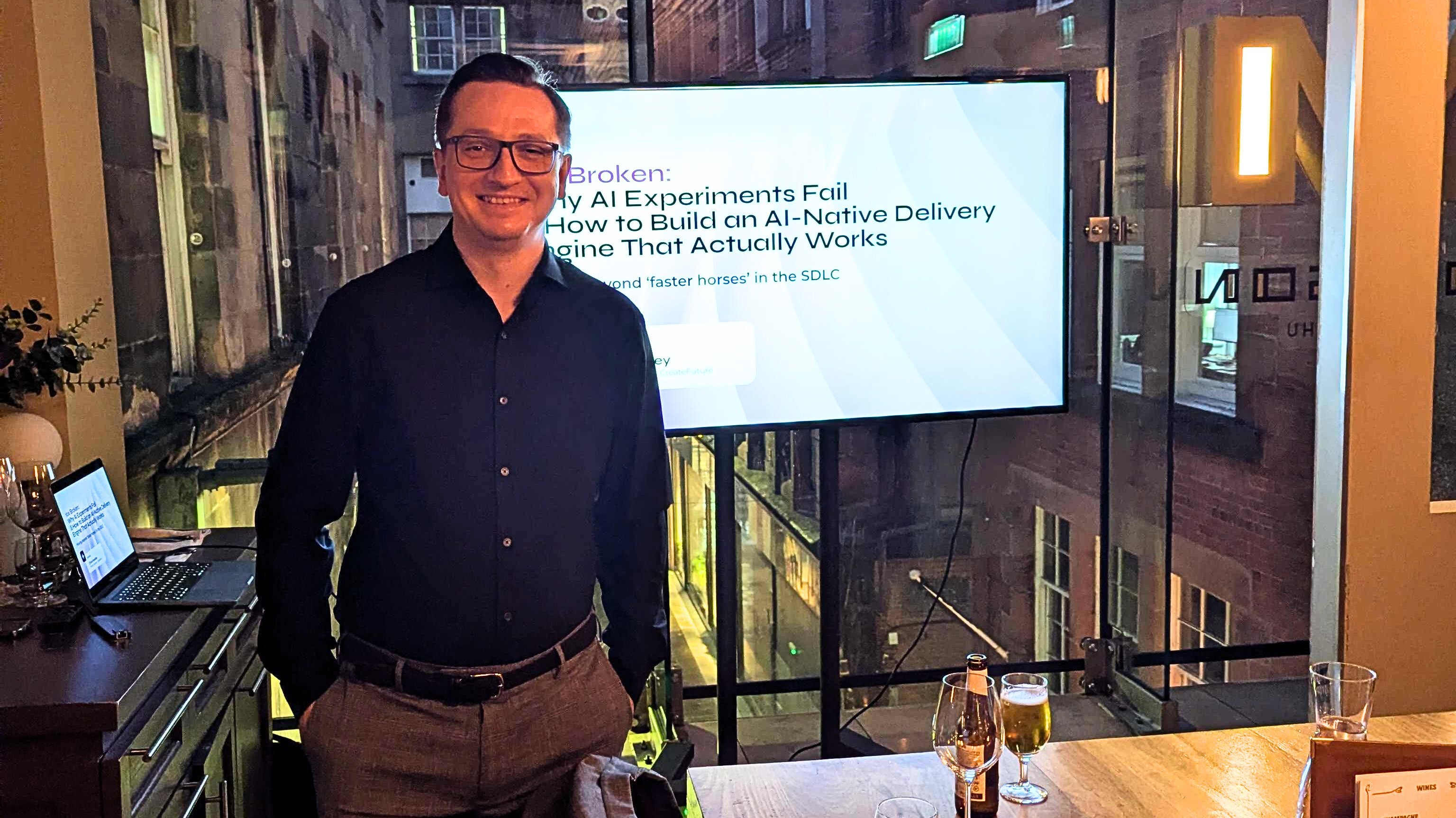 Chris Hawley presenting on AI-native delivery at a technology leadership event in Glasgow, standing in front of a screen titled “Why AI Experiments Fail: How to Build an AI-Native Delivery Engine That Actually Works.