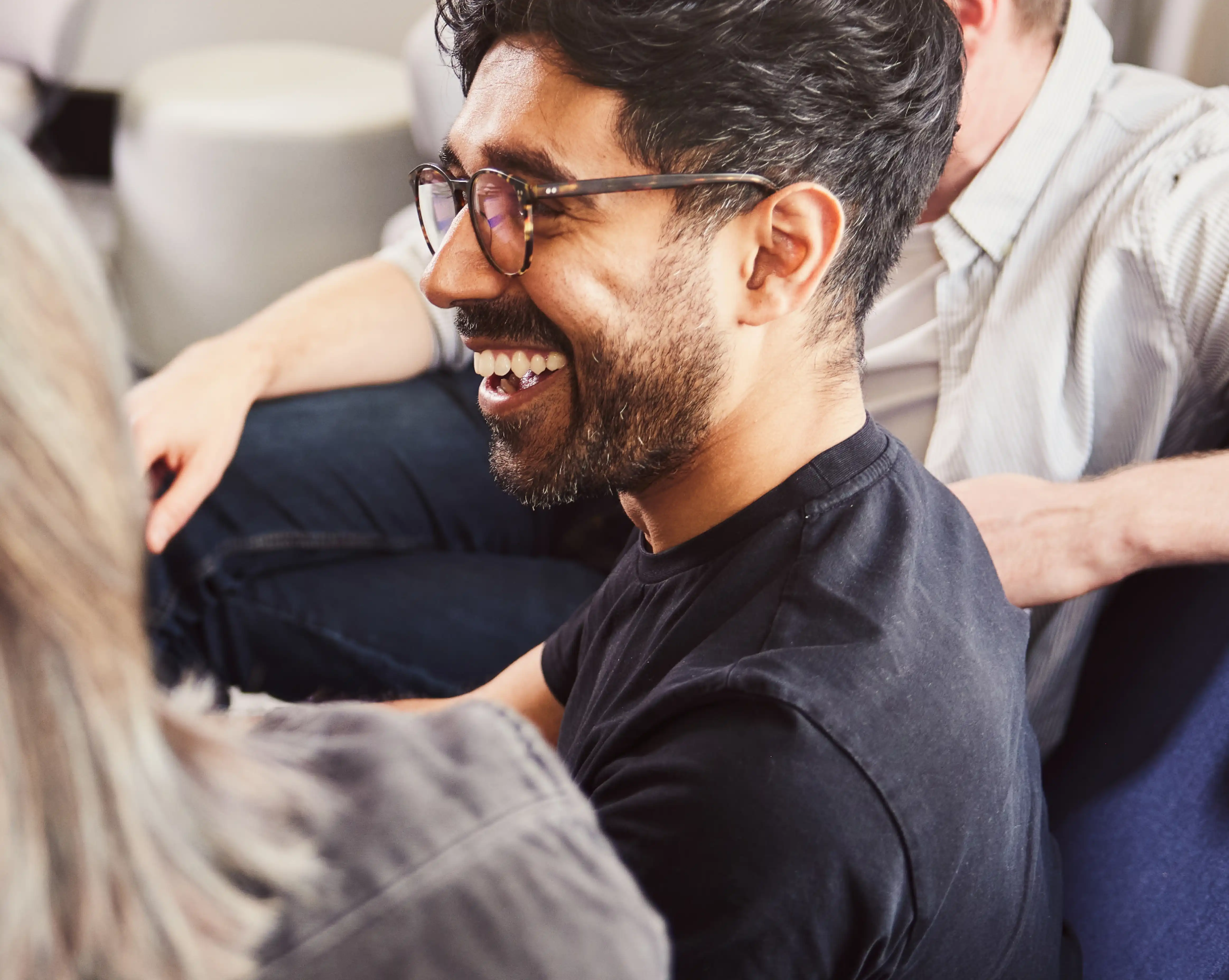 A person smiling while chatting to two colleagues sat beside them