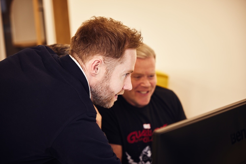 Two men examining a computer screen together.