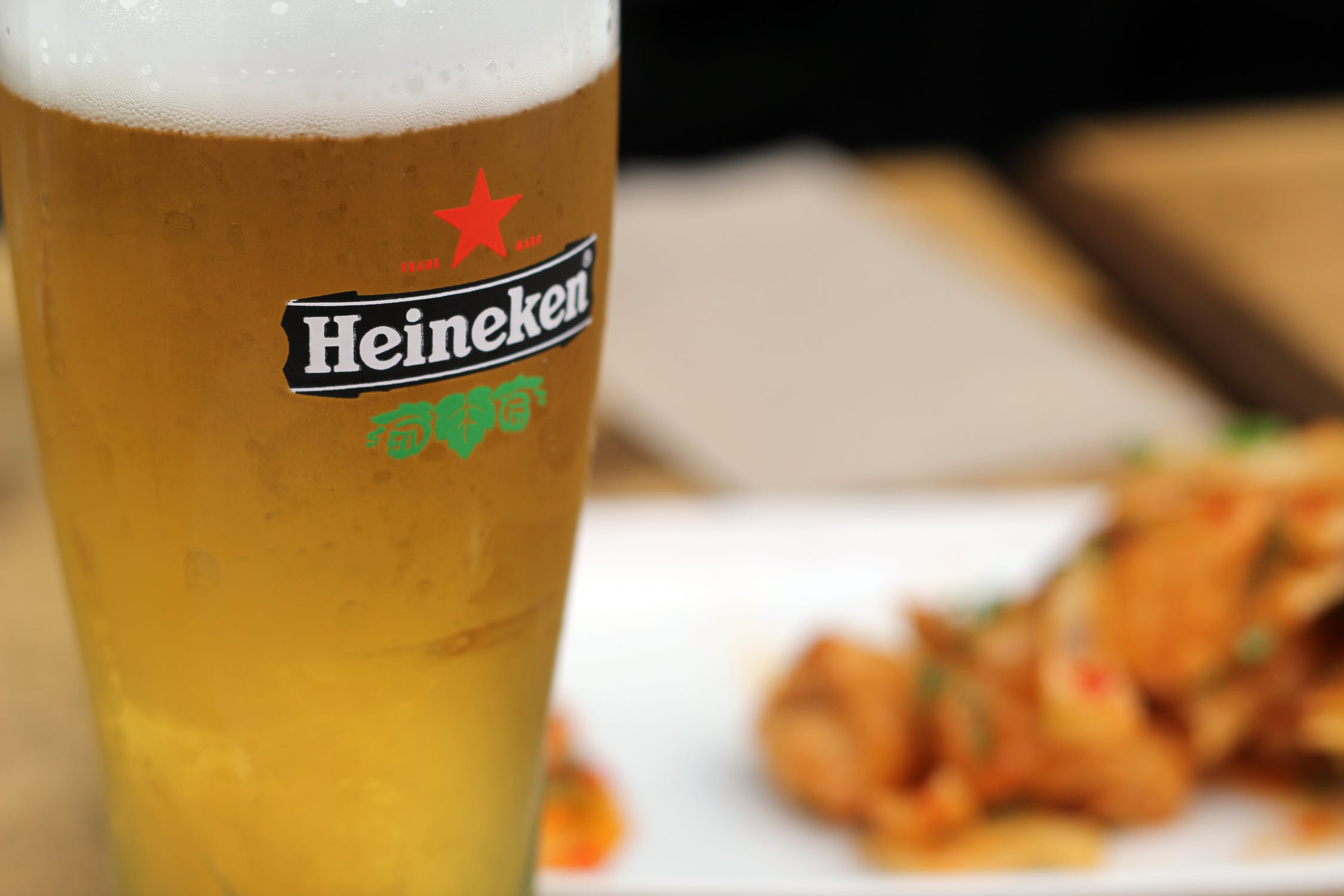 A pint of Heineken next to a meal.