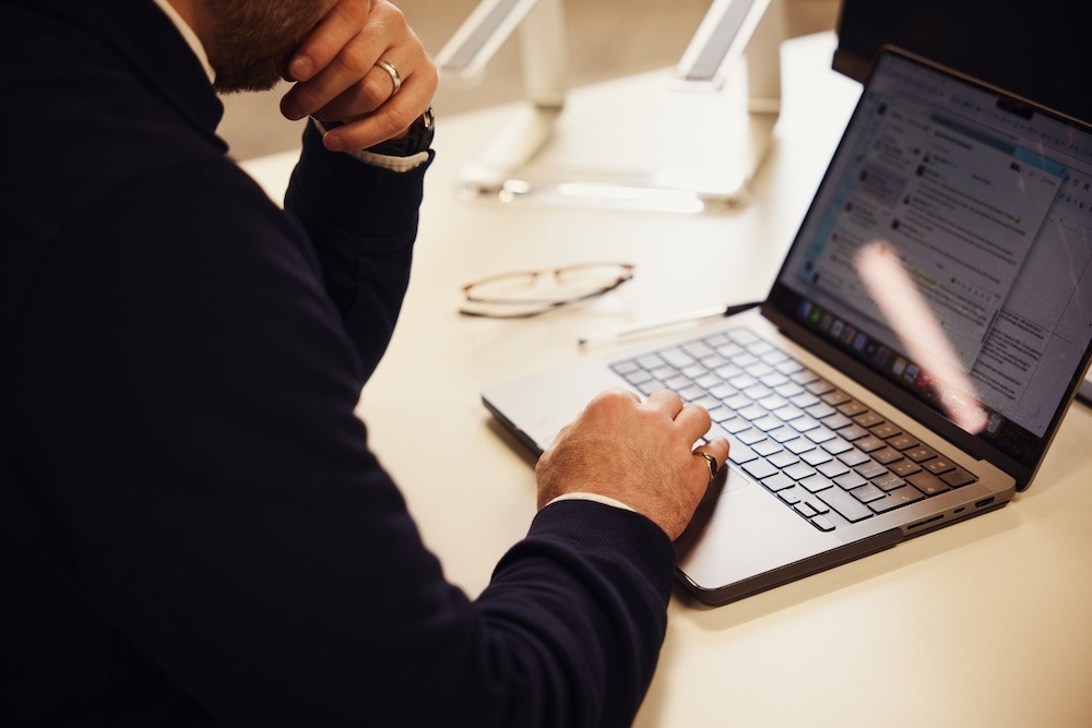 A man sitting at a desk focused on a laptop.