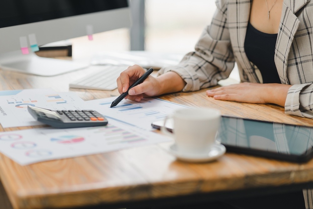 A businesswoman sitting at a desk with a calculator doing paperwork.