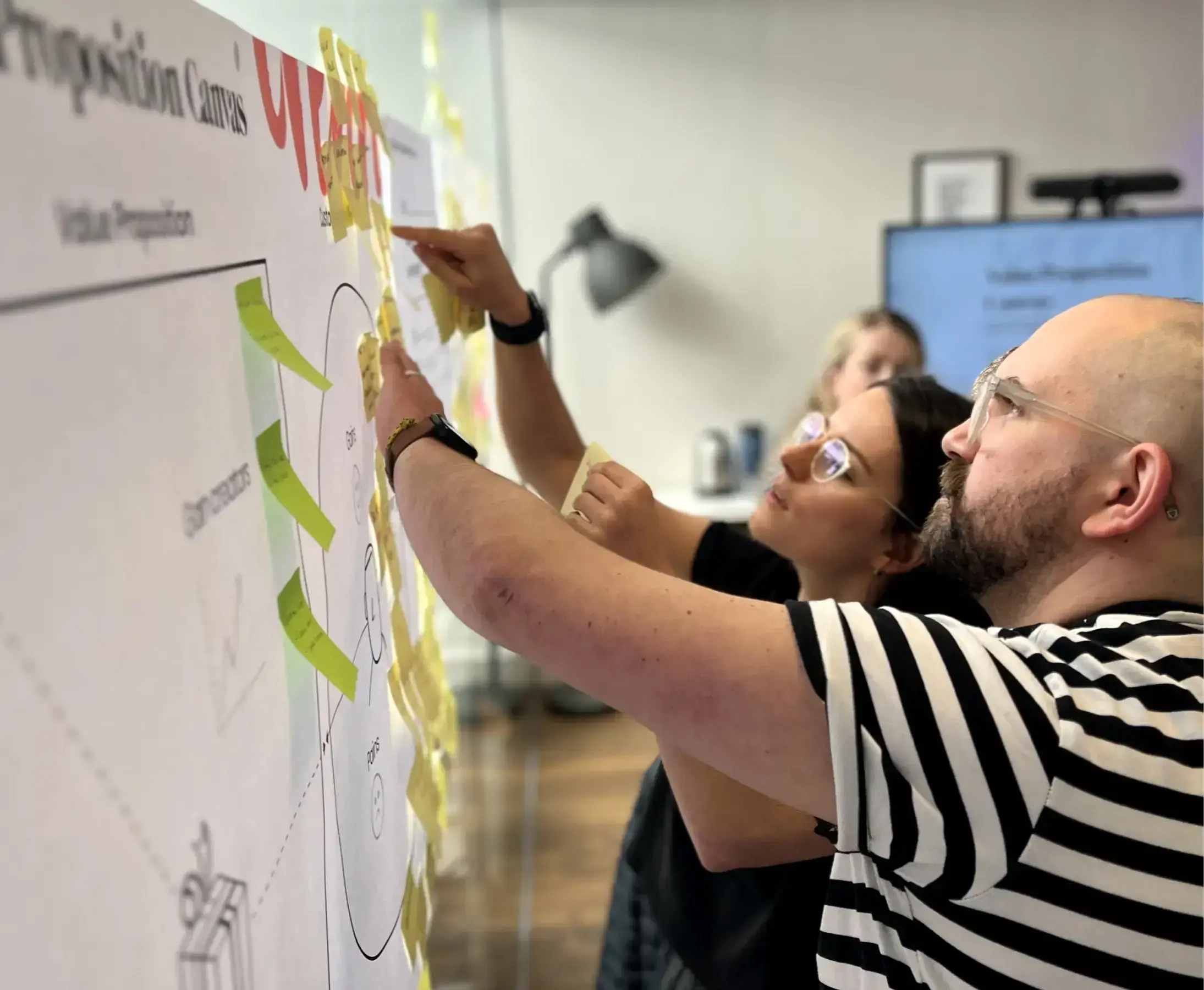 Two colleagues are collaborating and adding sticky notes to a whiteboard