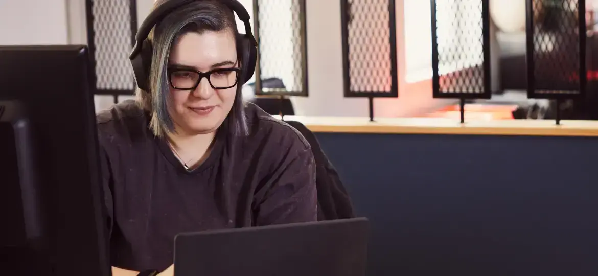 A colleague is wearing headphones and working on their laptop