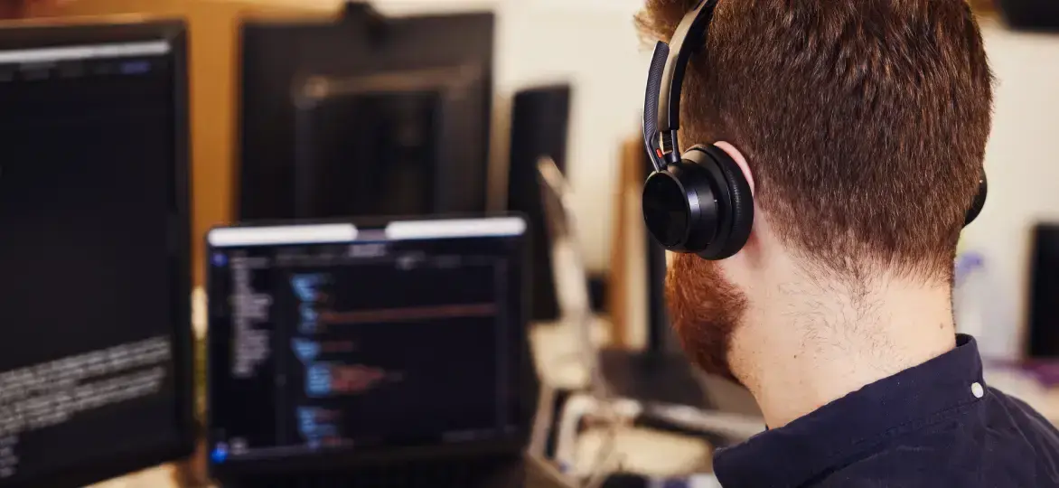 Back of a head with headphones looking at a screen