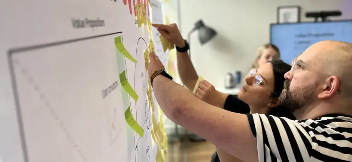 Two people moving sticky notes on a whiteboard