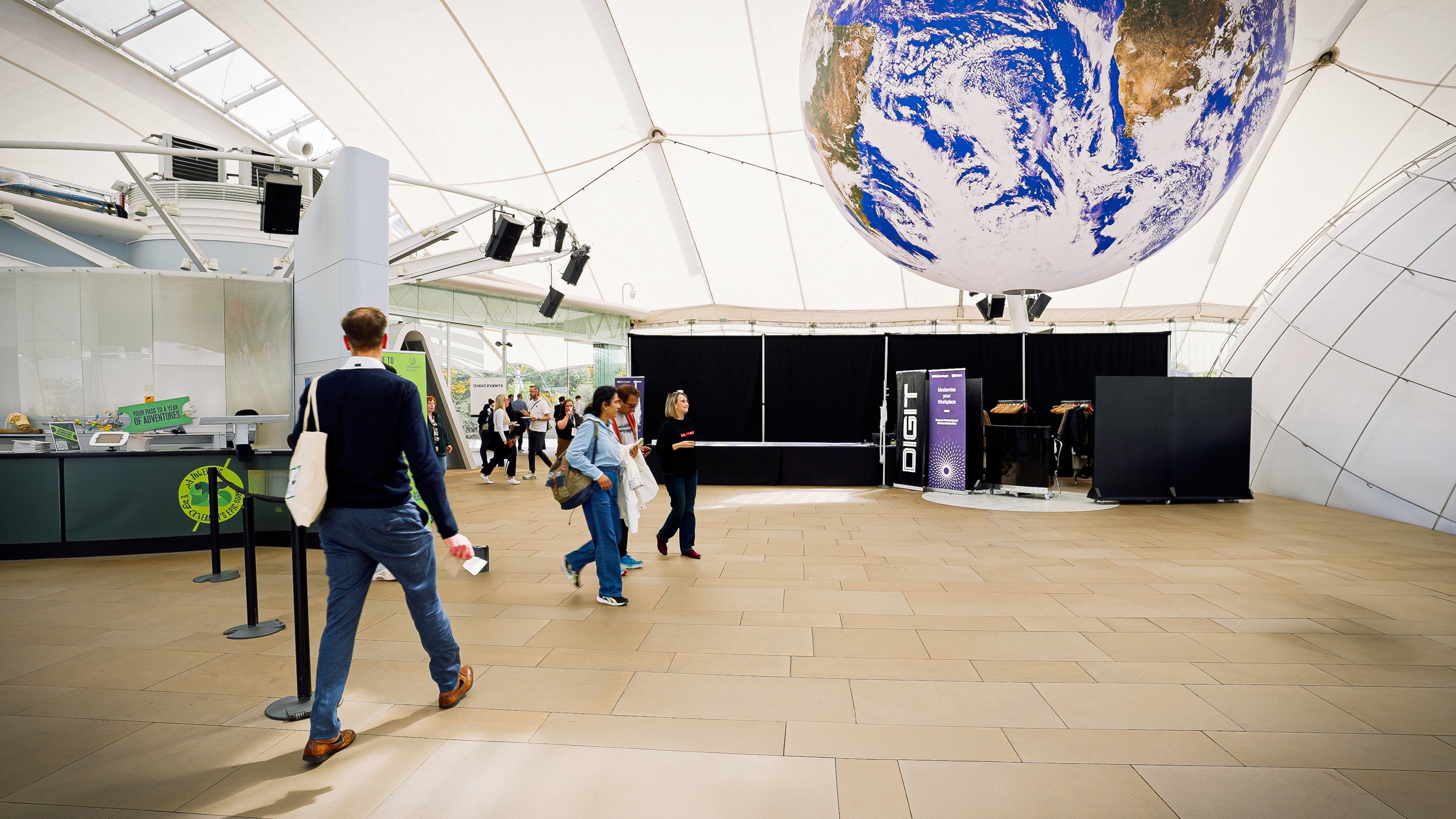 A person walking through an open conference space and a planet earth decoration hanging from the ceiling