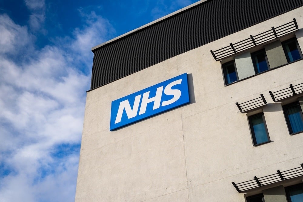 Corner of a building with a blue NHS sign on it